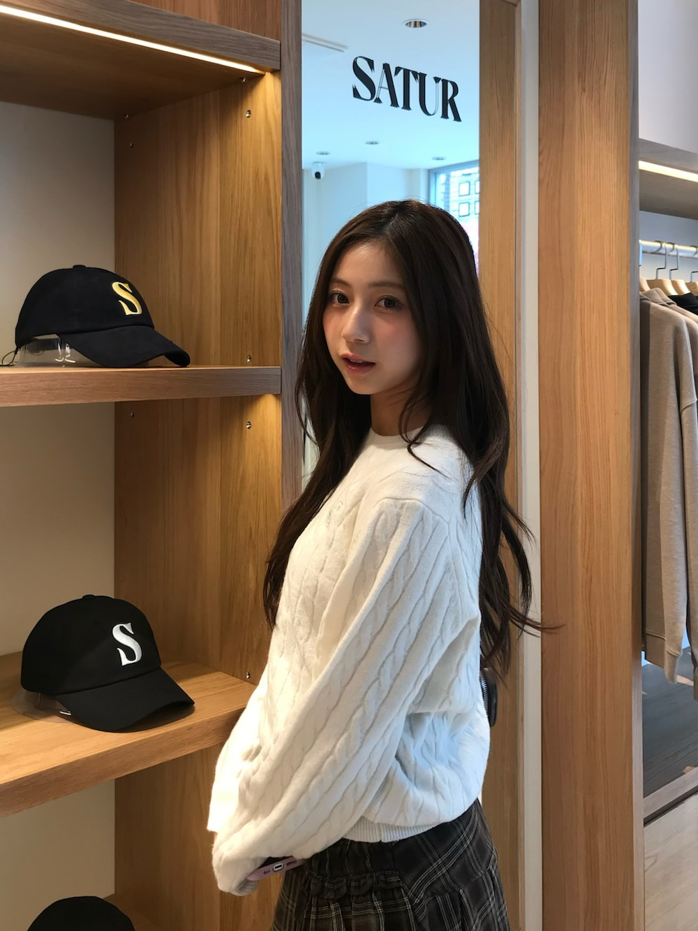 ブラウン系のスカート、ホワイト系のニット/セーター、ブラウン系のブーツを着用したレディースの秋コーディネートの2枚目の写真