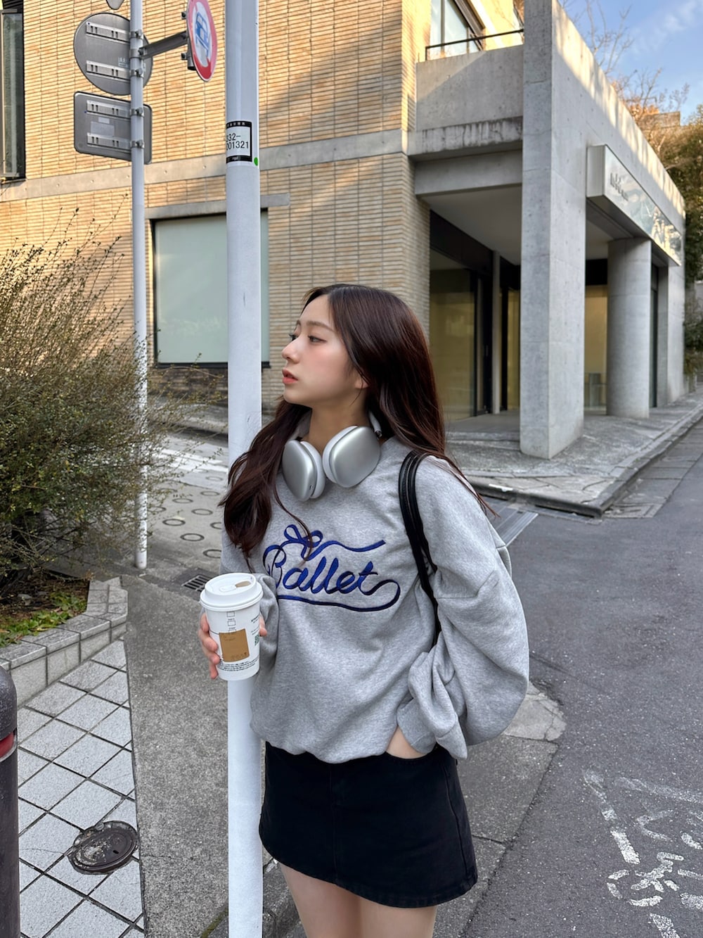 グレー系のスウェット、ブラック系のスカート、ベージュ系のスニーカーを着用したレディースの冬コーディネートの3枚目の写真