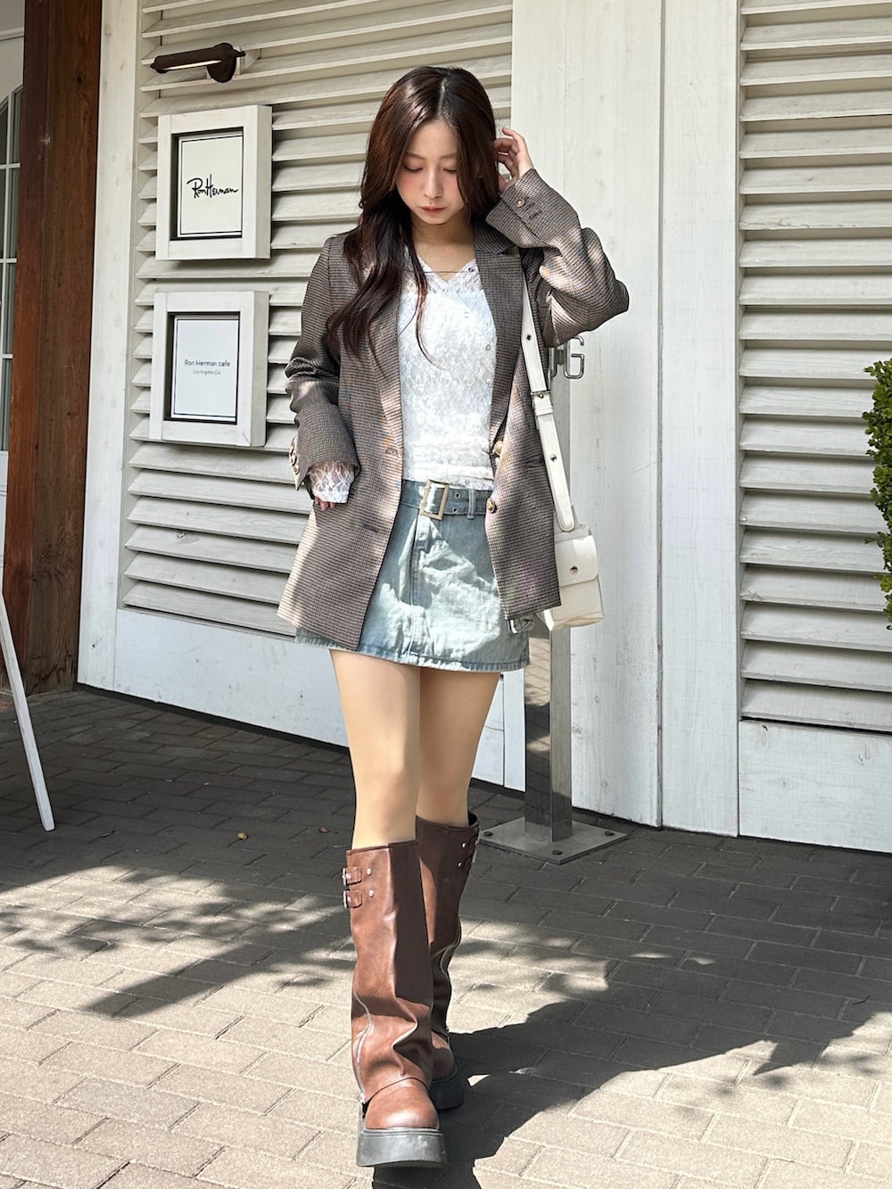 ブルー系のスカート、ホワイト系のトップス、ブラウン系のブーツを着用したレディースの春コーディネートの2枚目の写真