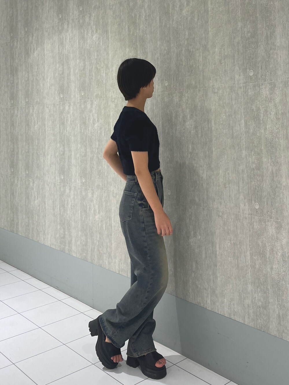 ブラック系のニット/セーター、ブルー系のデニムパンツ、ブラック系のサンダルを着用したレディースの夏コーディネートの2枚目の写真