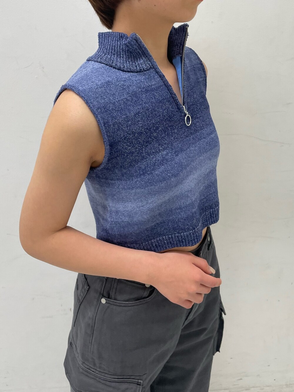 ブルー系のタンクトップ、ブラック系のデニムパンツ、ホワイト系のブーツを着用したレディースの春コーディネートの5枚目の写真