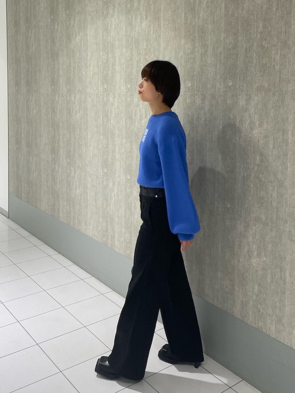 ブルー系のニット/セーター、ブラック系のデニムパンツ、グレー系のハンドバッグを着用したレディースの冬コーディネートの2枚目の写真