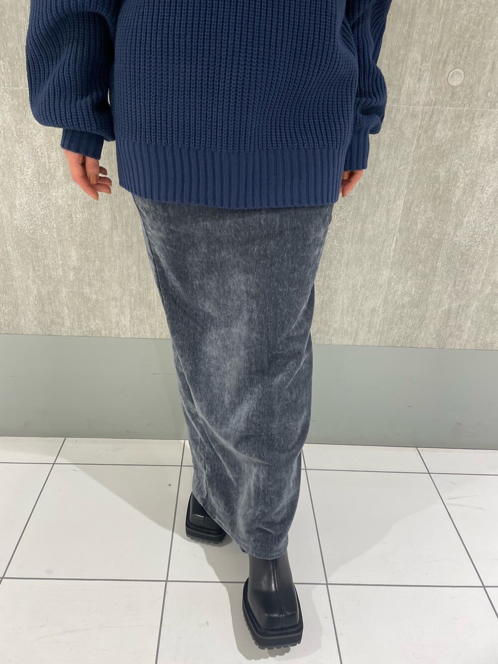 ブルー系のニット/セーター、ブラック系のブーツ、グレー系のスカートを着用したレディースの秋コーディネートの5枚目の写真