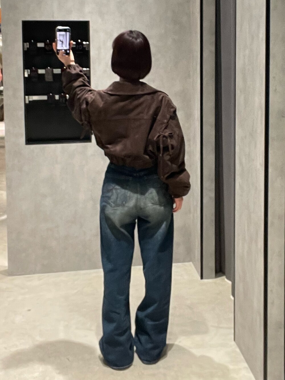 ブラック系のTシャツ/カットソー、ブラウン系のブルゾン、ブルー系のデニムパンツを着用したレディースの秋コーディネートの5枚目の写真
