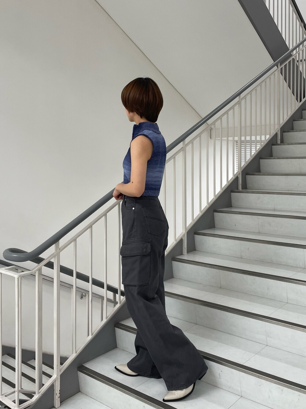 ブルー系のタンクトップ、ブラック系のデニムパンツ、ホワイト系のブーツを着用したレディースの春コーディネートの2枚目の写真