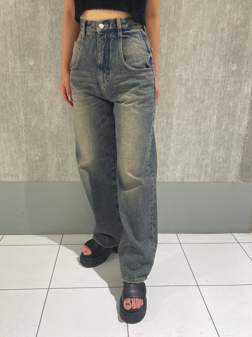 ブラック系のニット/セーター、ブルー系のデニムパンツ、ブラック系のサンダルを着用したレディースの夏コーディネートの5枚目の写真