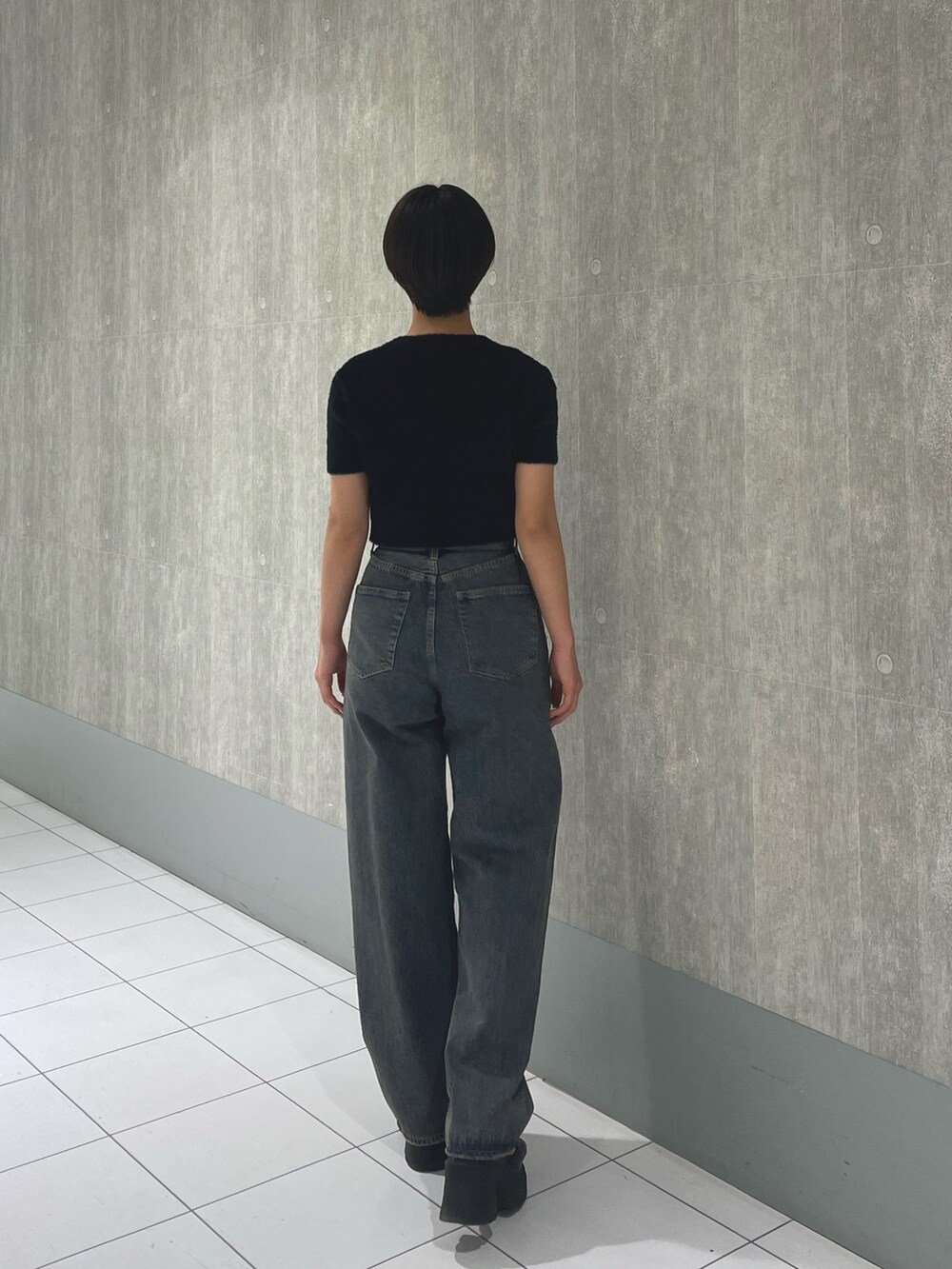 ブラック系のニット/セーター、ブルー系のデニムパンツ、ブラック系のサンダルを着用したレディースの夏コーディネートの3枚目の写真