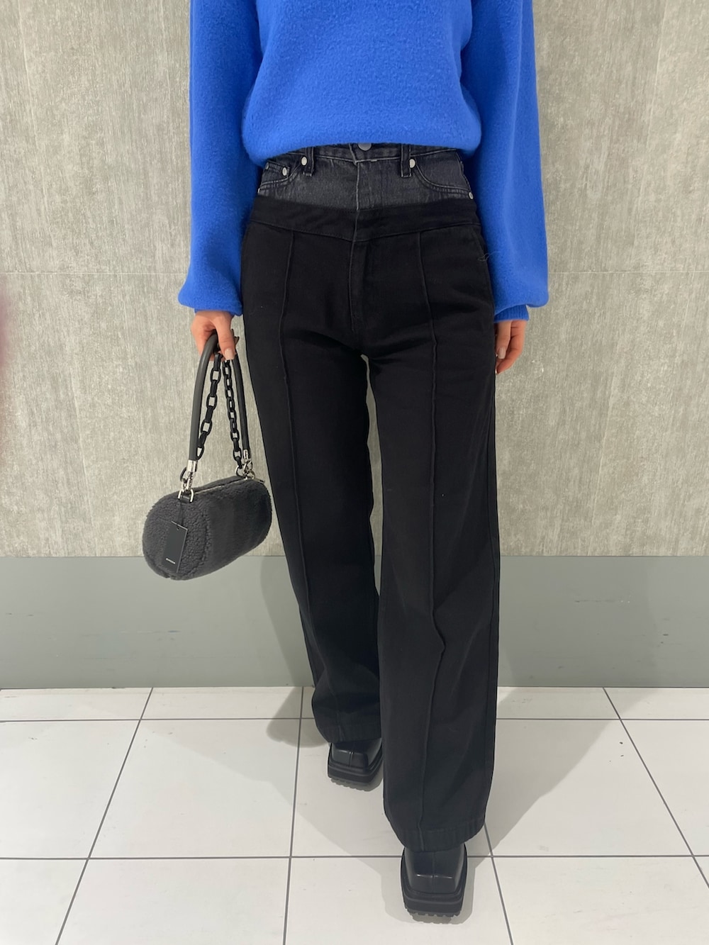 ブルー系のニット/セーター、ブラック系のデニムパンツ、グレー系のハンドバッグを着用したレディースの冬コーディネートの4枚目の写真