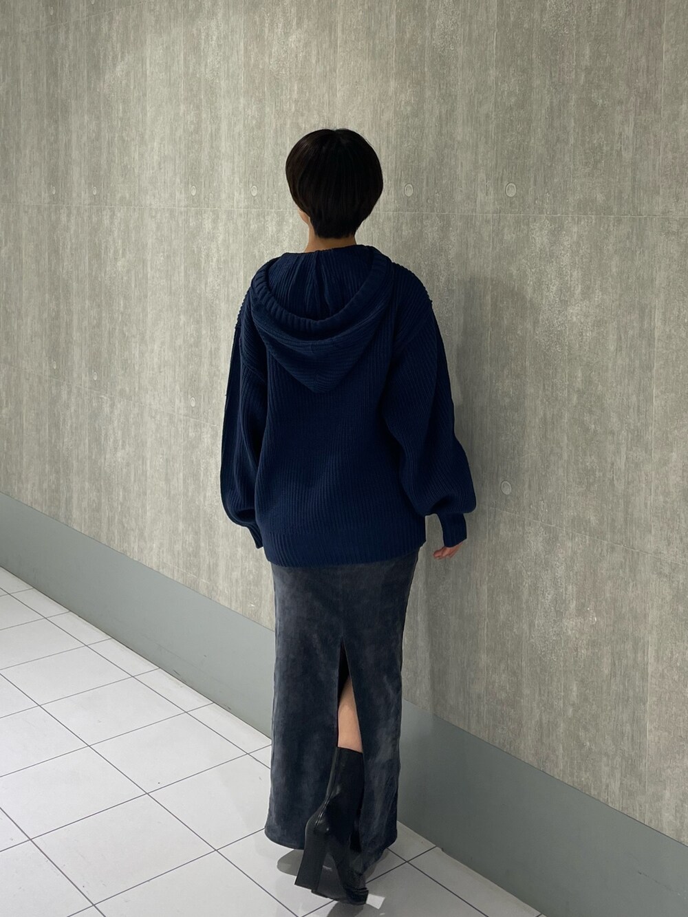 ブルー系のニット/セーター、ブラック系のブーツ、グレー系のスカートを着用したレディースの秋コーディネートの2枚目の写真