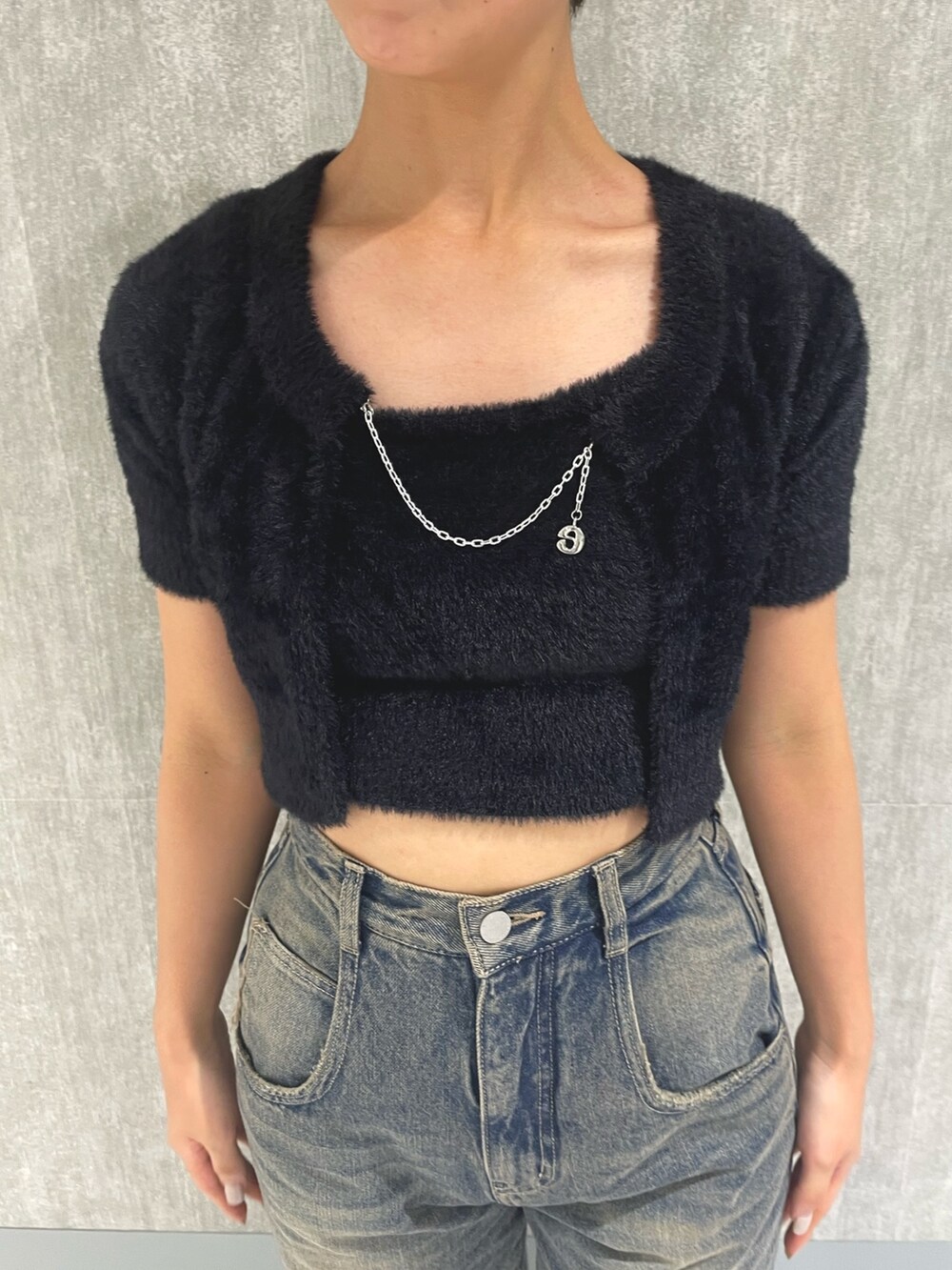 ブラック系のニット/セーター、ブルー系のデニムパンツ、ブラック系のサンダルを着用したレディースの夏コーディネートの4枚目の写真