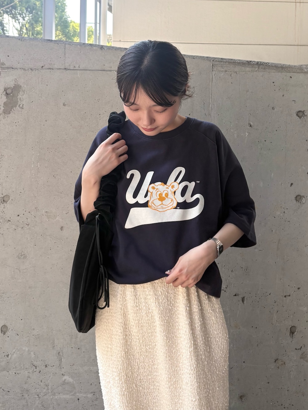 ブルー系のTシャツ/カットソー、ホワイト系のスカート、ブラック系のショルダーバッグを着用したレディースの秋コーディネートの3枚目の写真