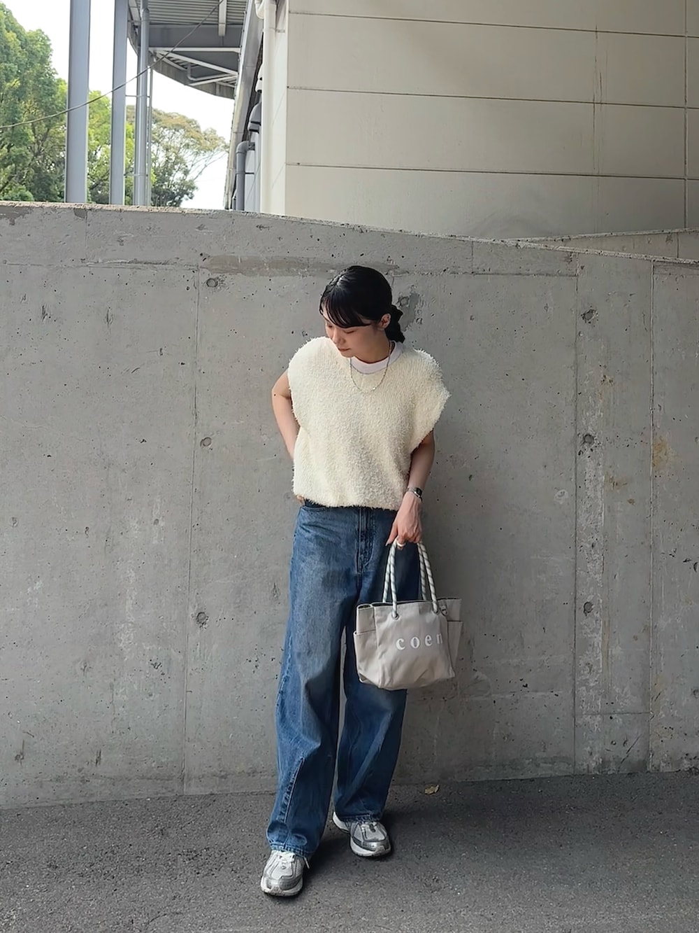 ホワイト系のベスト、ブルー系のデニムパンツ、グレー系のトートバッグを着用したレディースの夏コーディネートの2枚目の写真