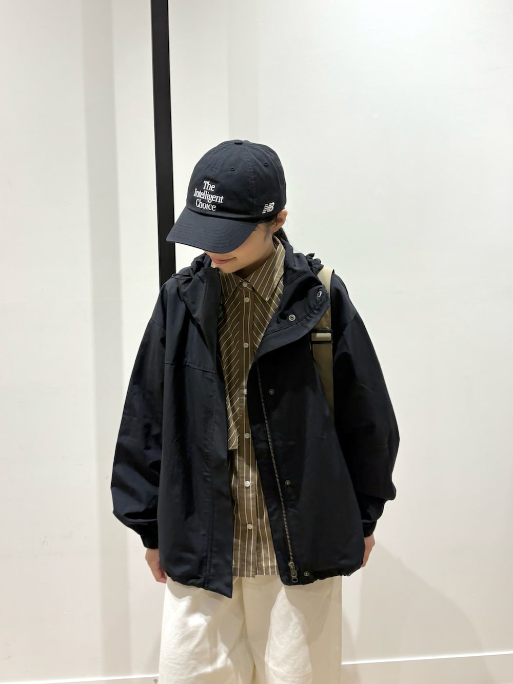 ブラウン系のシャツ/ブラウス、ブラック系のマウンテンパーカー、ホワイト系のデニムパンツを着用したレディースの春コーディネートの3枚目の写真