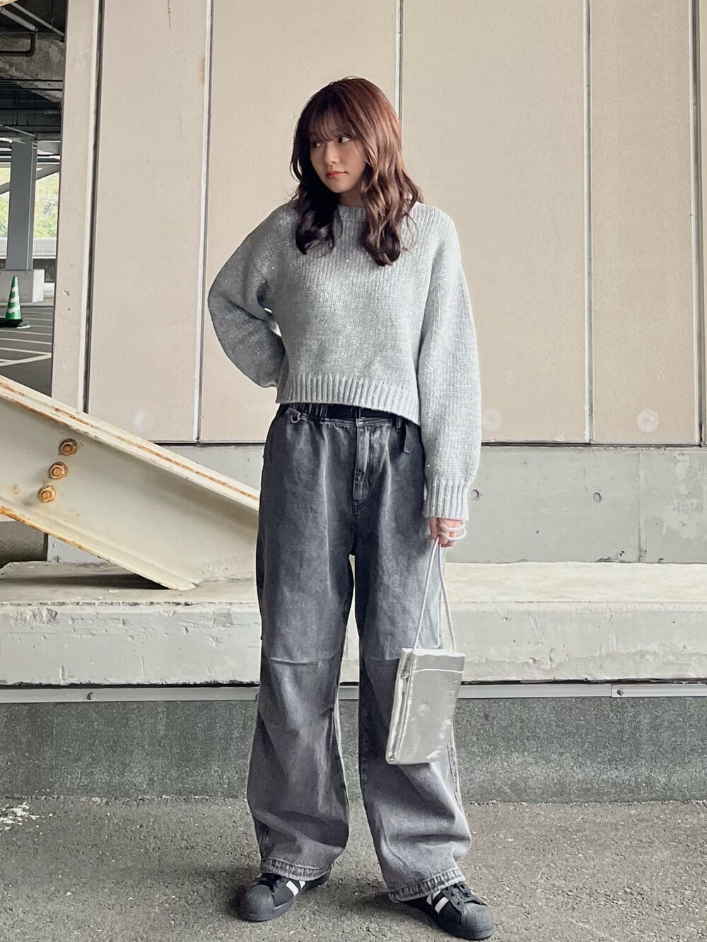 グレー系のニット/セーター、グレー系のデニムパンツ、シルバー系のショルダーバッグを着用したレディースの冬コーディネートの4枚目の写真