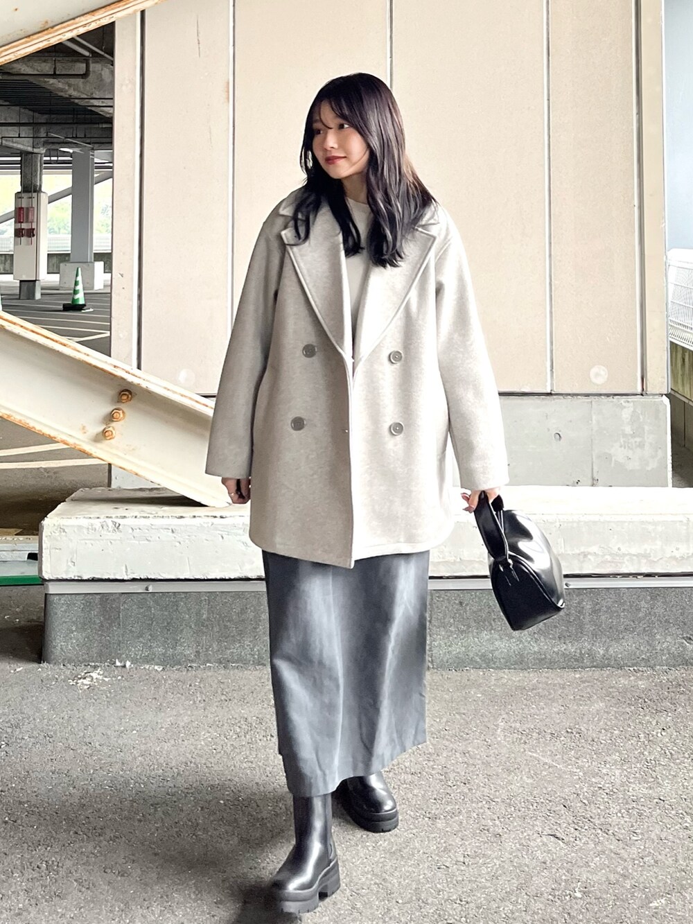 ホワイト系のニット/セーター、グレー系のジャンパースカート、グレー系のその他アウターを着用したレディースの冬コーディネートの2枚目の写真