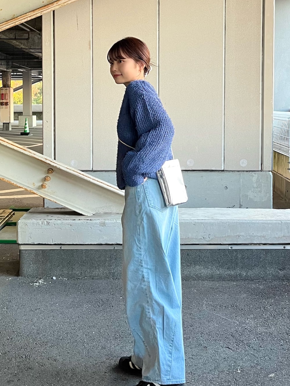 シルバー系のショルダーバッグ、ブルー系のデニムパンツ、ブルー系のニット/セーターを着用したレディースの冬コーディネートの3枚目の写真