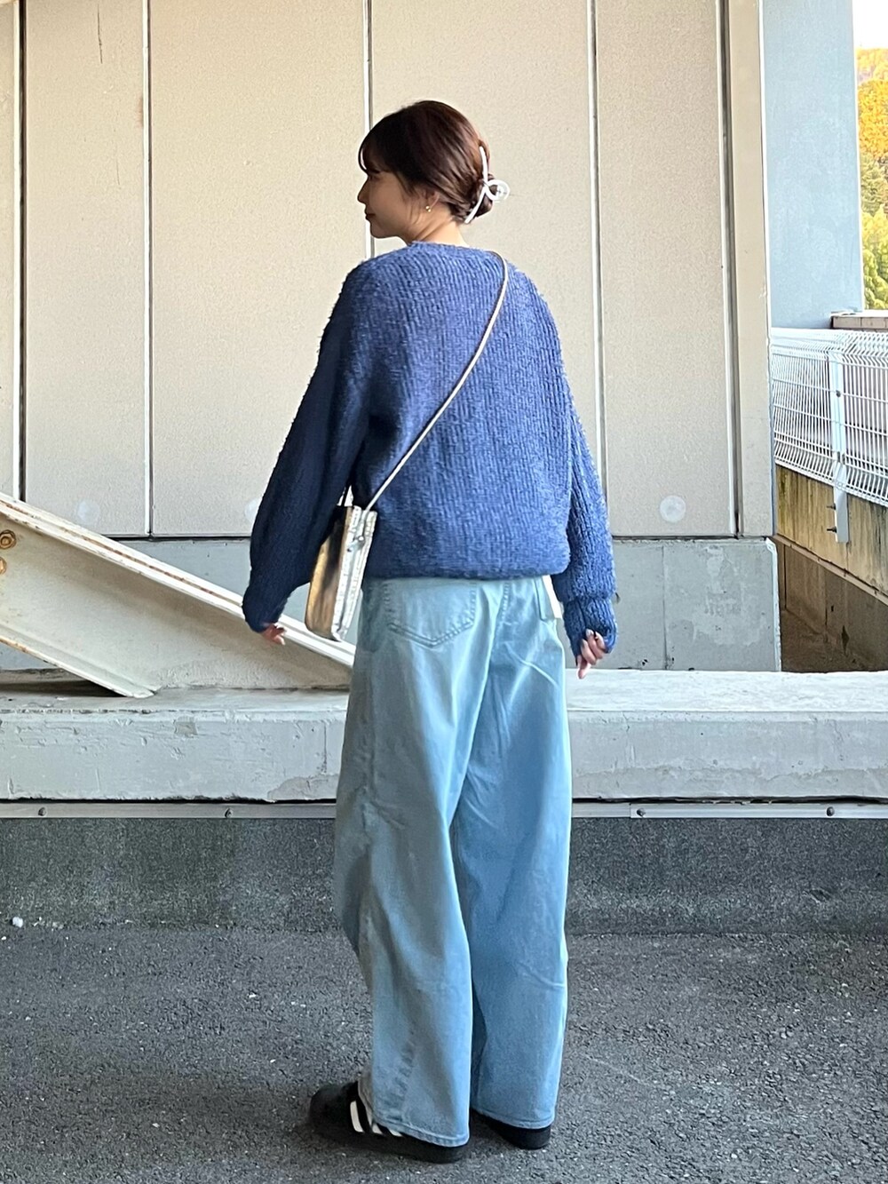 シルバー系のショルダーバッグ、ブルー系のデニムパンツ、ブルー系のニット/セーターを着用したレディースの冬コーディネートの2枚目の写真