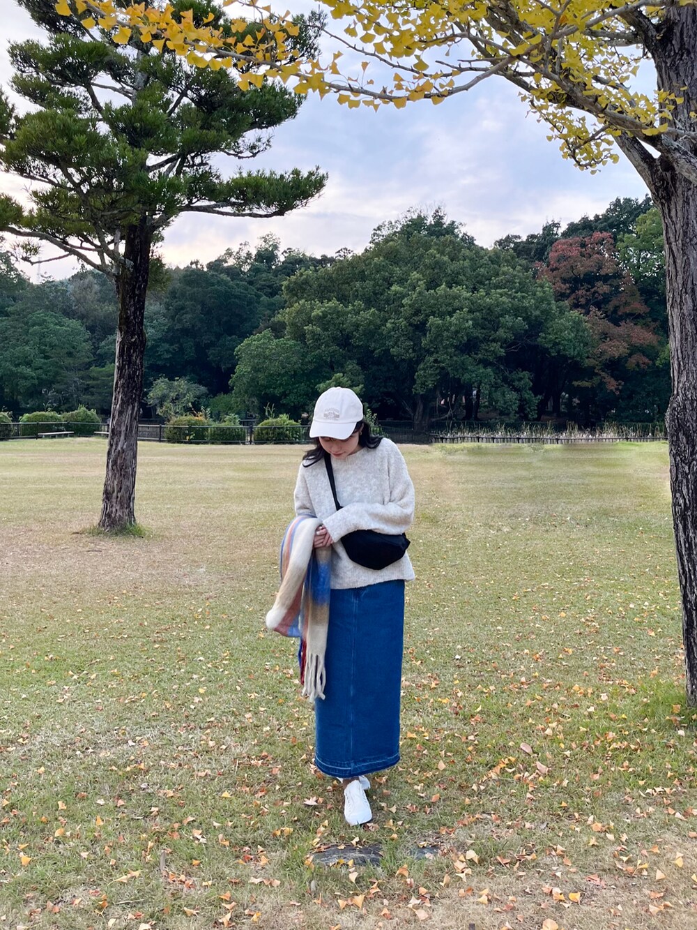 ホワイト系のニット/セーター、ブルー系のデニムスカート、ブラック系のボディバッグ/ウエストポーチを着用したレディースの秋コーディネートの3枚目の写真