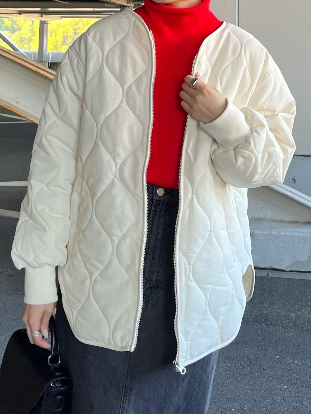 ホワイト系のノーカラージャケット、レッド系のニット/セーター、ブラック系のデニムスカートを着用したレディースの秋コーディネートの3枚目の写真