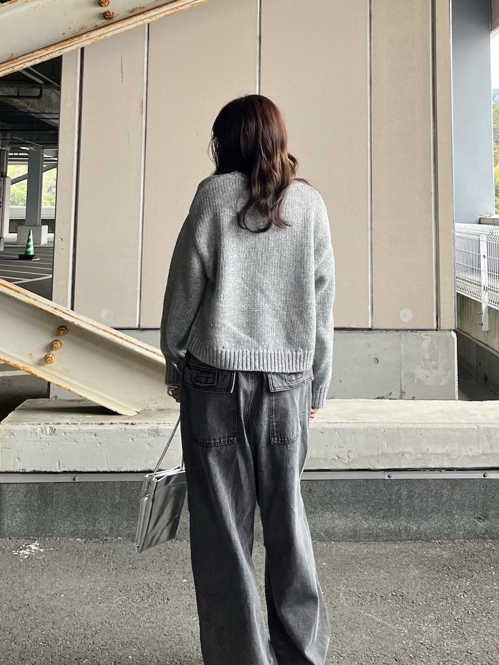 グレー系のニット/セーター、グレー系のデニムパンツ、シルバー系のショルダーバッグを着用したレディースの冬コーディネートの3枚目の写真
