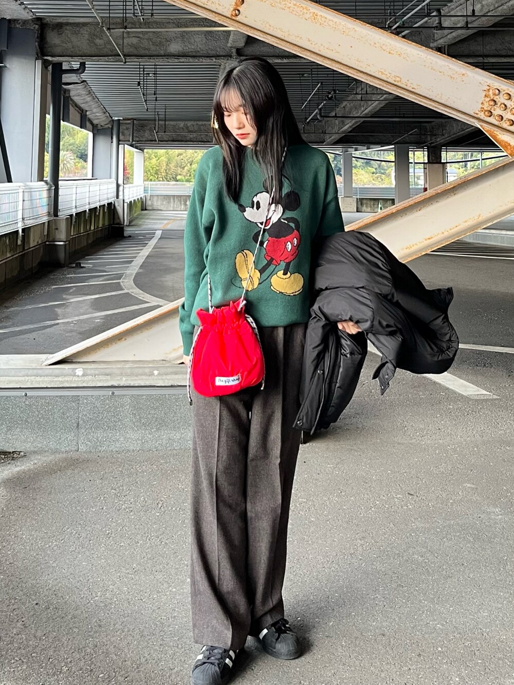 ブラック系のその他アウター、グリーン系のニット/セーター、ブラウン系のスラックスを着用したレディースの冬コーディネートの3枚目の写真