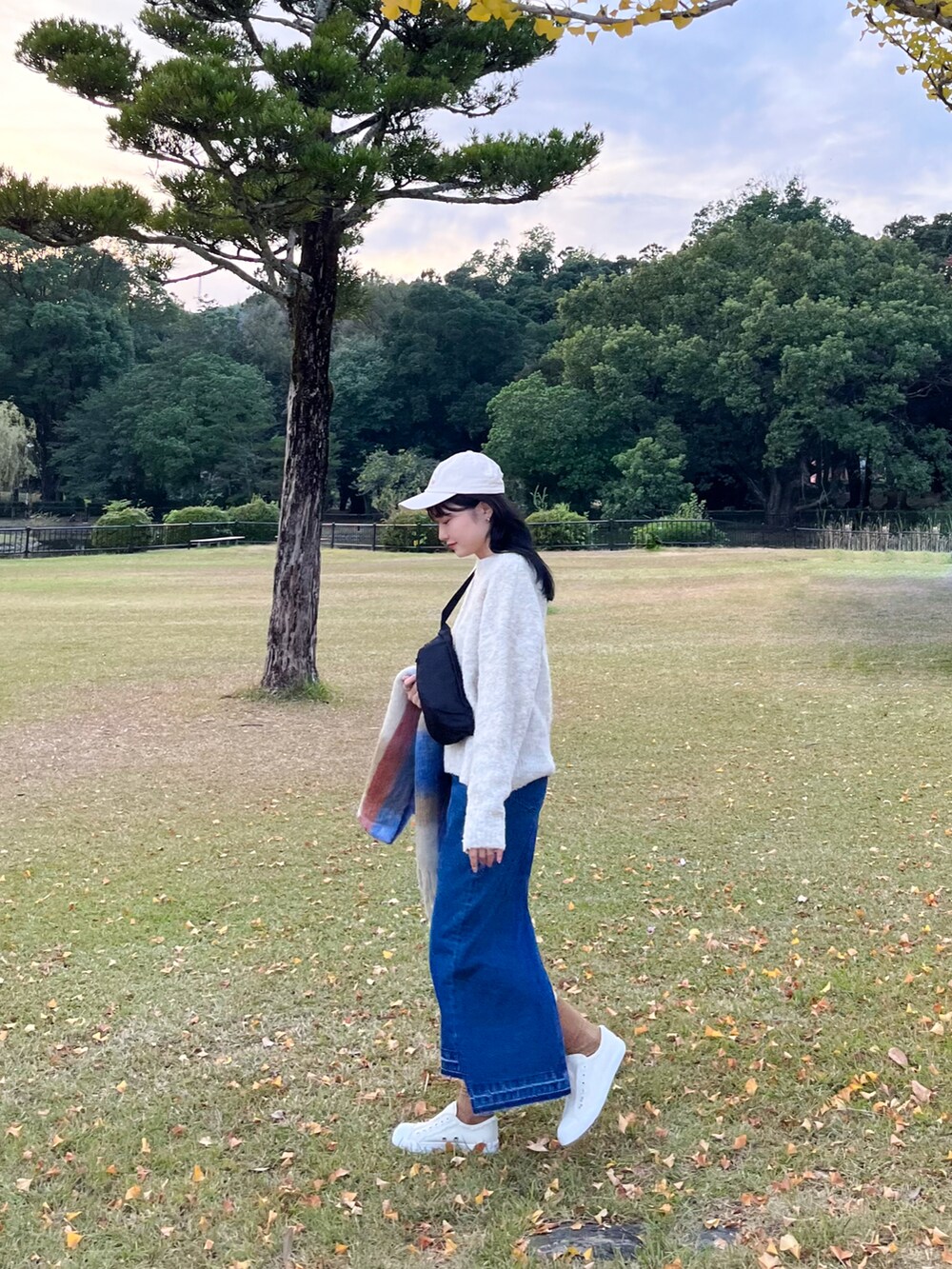 ホワイト系のニット/セーター、ブルー系のデニムスカート、ブラック系のボディバッグ/ウエストポーチを着用したレディースの秋コーディネートの2枚目の写真