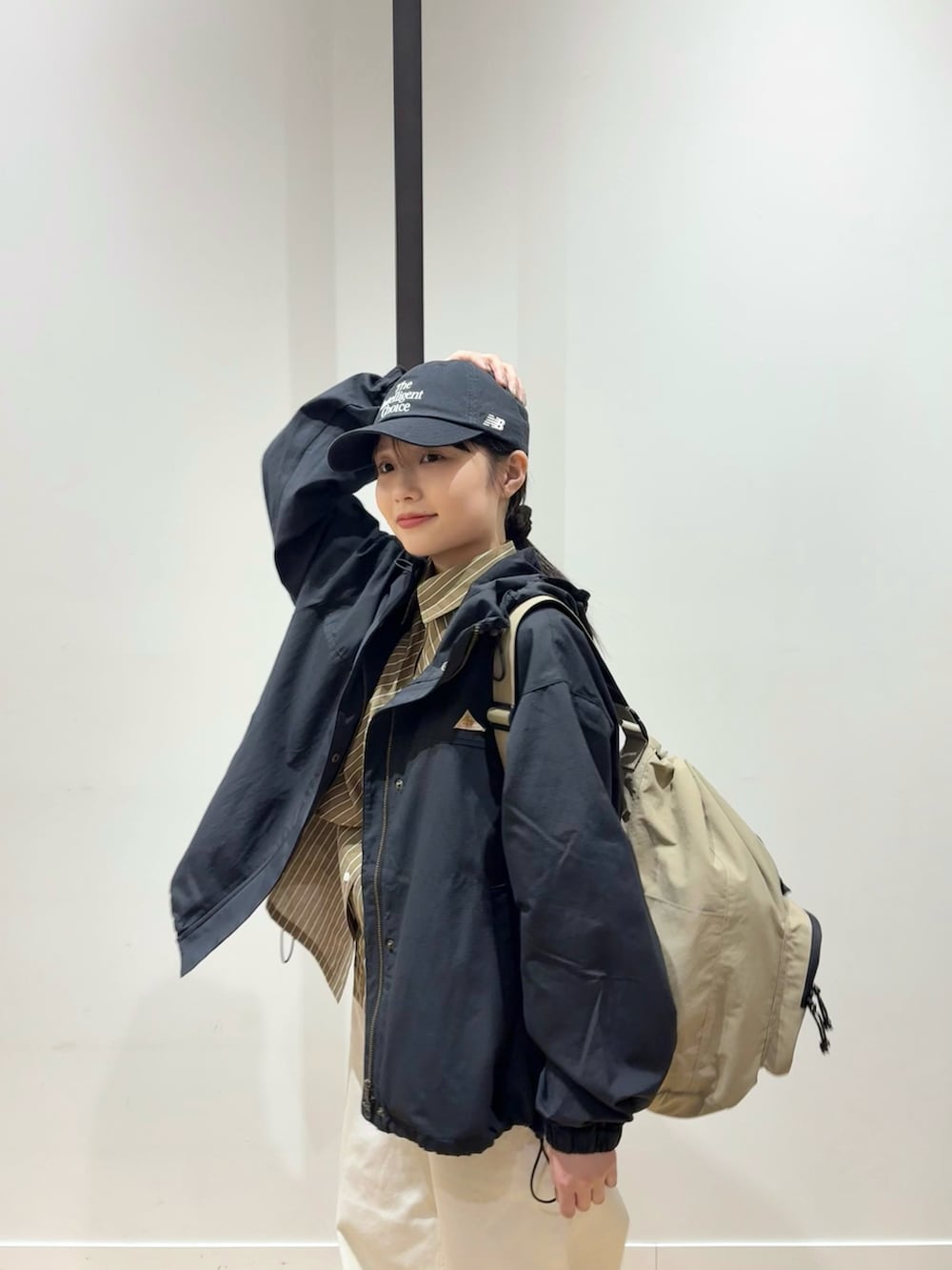 ブラウン系のシャツ/ブラウス、ブラック系のマウンテンパーカー、ホワイト系のデニムパンツを着用したレディースの春コーディネートの2枚目の写真