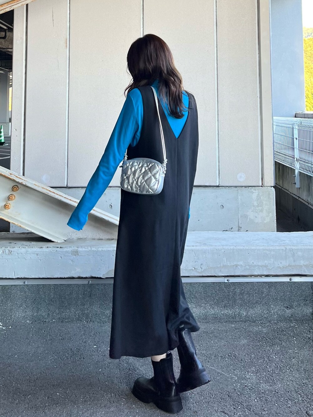 ブラック系のブーツ、ブラック系のジャンパースカート、ブルー系のTシャツ/カットソーを着用したレディースの冬コーディネートの4枚目の写真