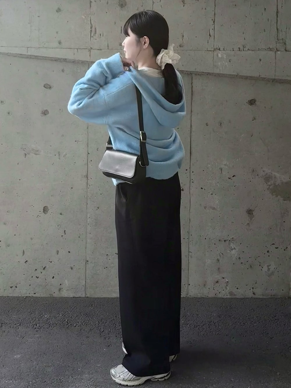 ブラック系のスラックス、ブルー系のニット/セーター、ホワイト系のスニーカーを着用したレディースの冬コーディネートの2枚目の写真