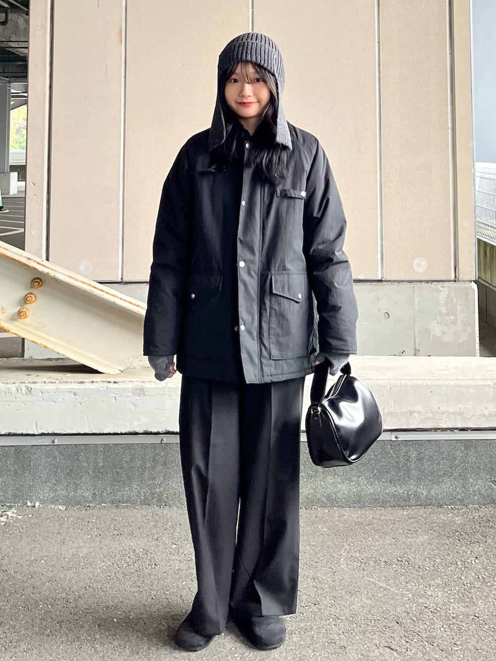 ブラック系のブルゾン、ブラック系のスラックス、ブラック系のショルダーバッグを着用したレディースの冬コーディネートの3枚目の写真