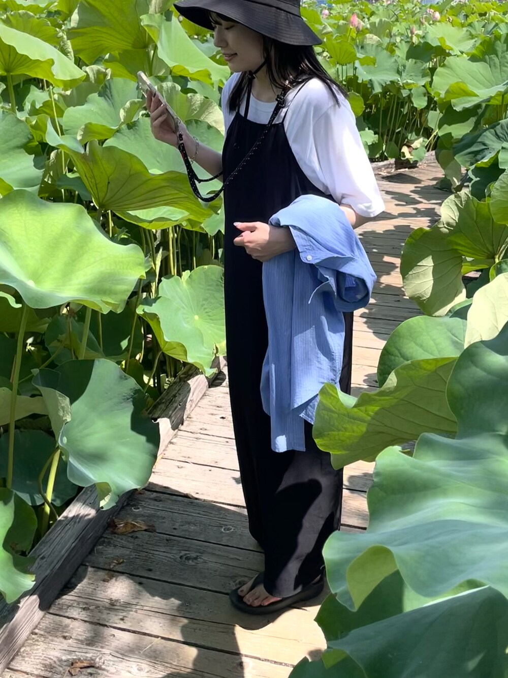 ブルー系のシャツ/ブラウス、ブラック系のワンピース、ブラック系のショルダーバッグを着用したレディースの夏コーディネートの2枚目の写真