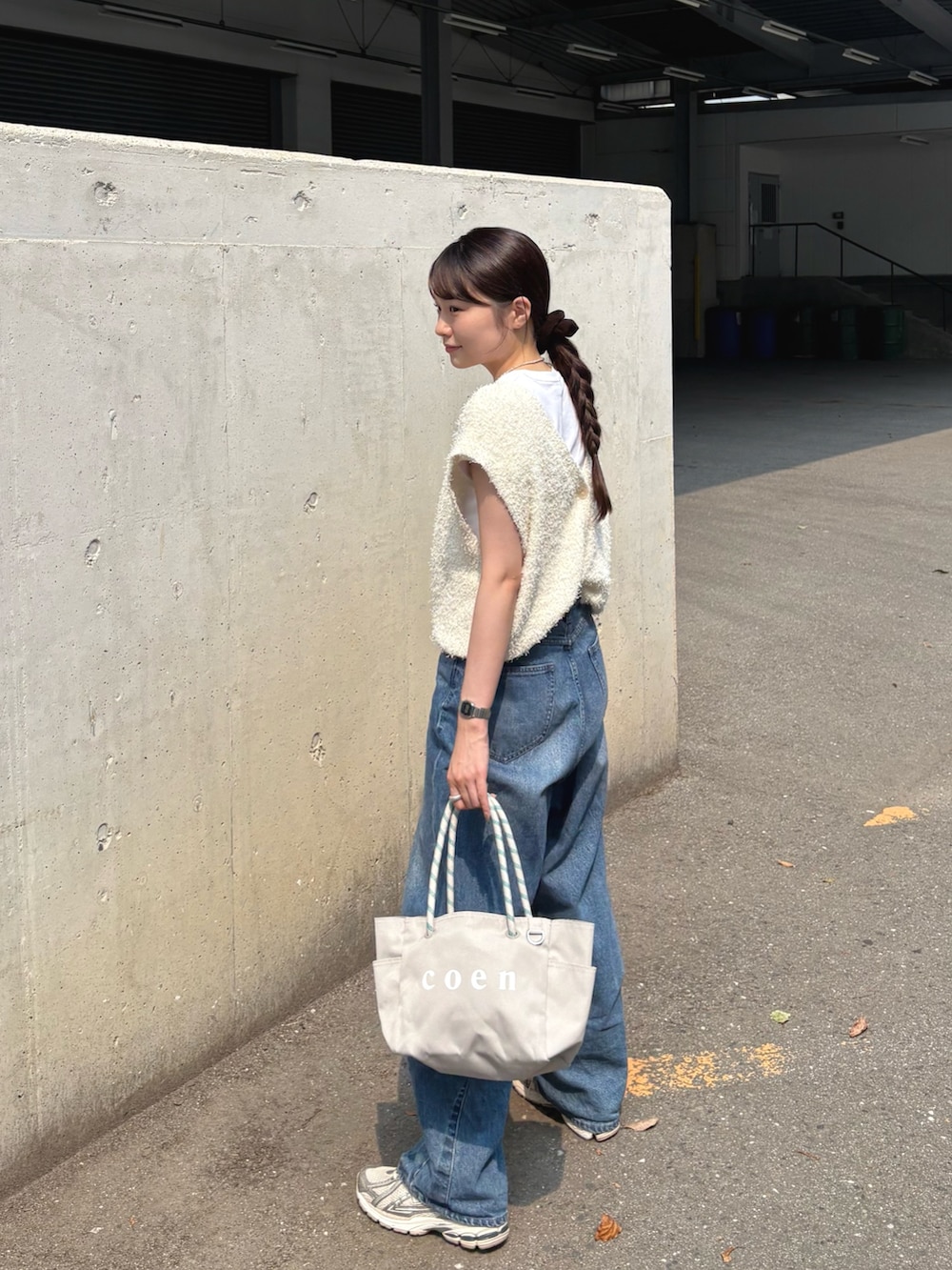 ホワイト系のベスト、ブルー系のデニムパンツ、グレー系のトートバッグを着用したレディースの夏コーディネートの3枚目の写真