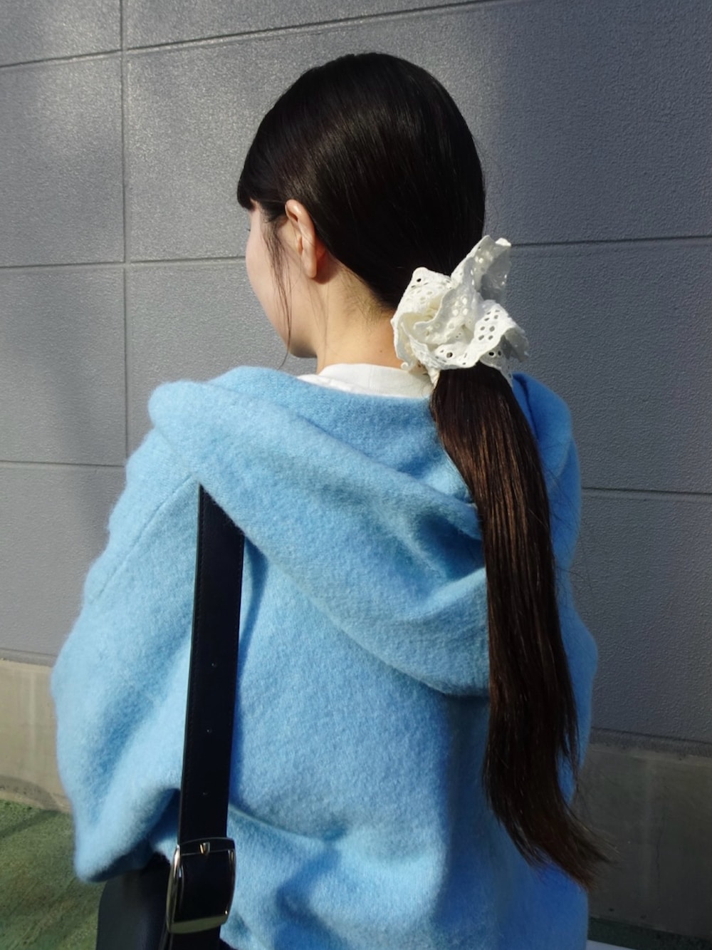 ブラック系のスラックス、ブルー系のニット/セーター、ホワイト系のスニーカーを着用したレディースの冬コーディネートの6枚目の写真