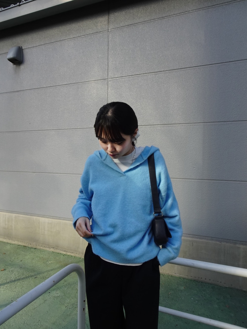 ブラック系のスラックス、ブルー系のニット/セーター、ホワイト系のスニーカーを着用したレディースの冬コーディネートの3枚目の写真