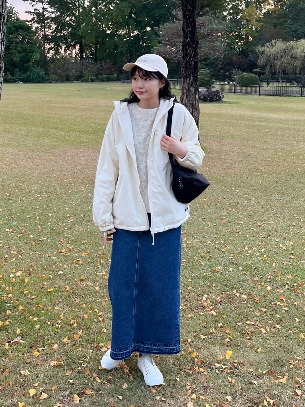 ホワイト系のニット/セーター、ブルー系のデニムスカート、ブラック系のボディバッグ/ウエストポーチを着用したレディースの秋コーディネートの4枚目の写真