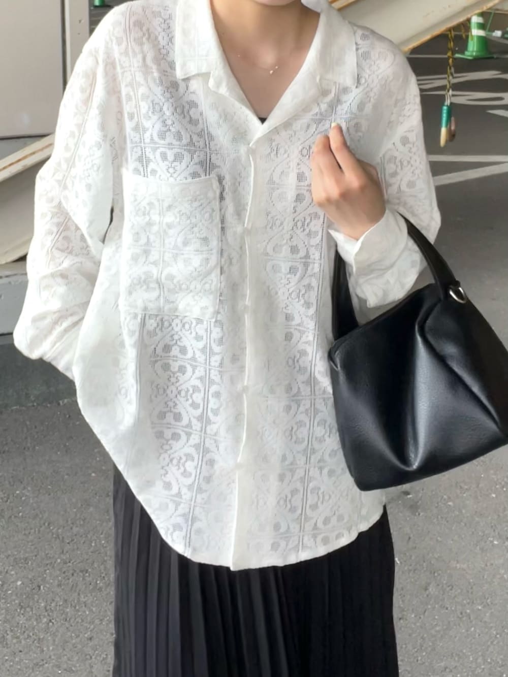 ブラック系のショルダーバッグ、ブラック系のスカート、ホワイト系のシャツ/ブラウスを着用したレディースの夏コーディネートの2枚目の写真