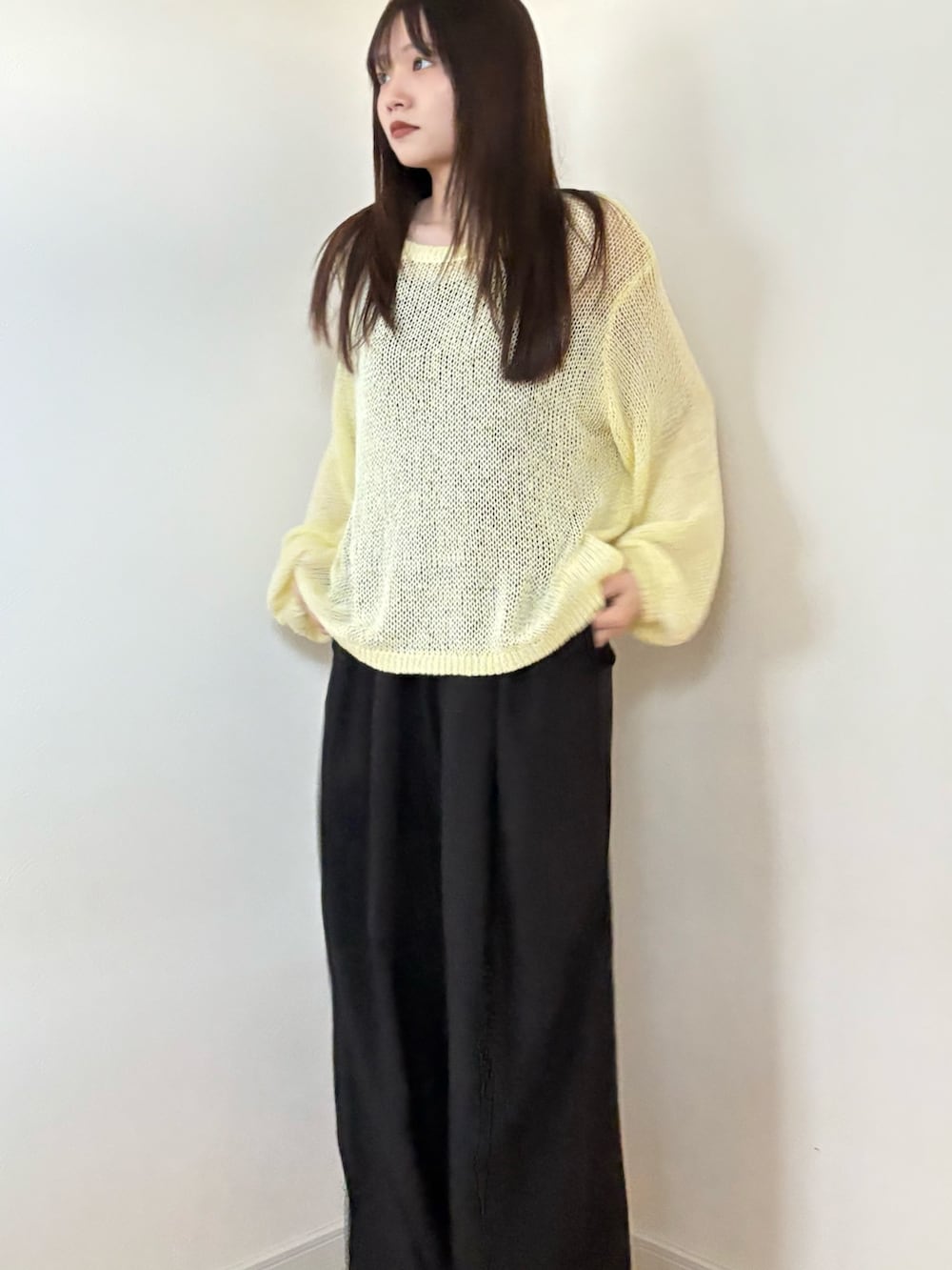 イエロー系のニット/セーター、ブラック系のスラックスを着用したレディースの春コーディネートの2枚目の写真