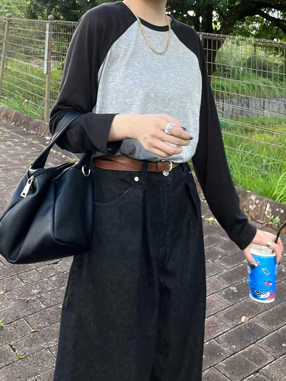 グレー系のTシャツ/カットソー、ブラック系のデニムパンツ、ホワイト系のスニーカーを着用したレディースの秋コーディネートの3枚目の写真