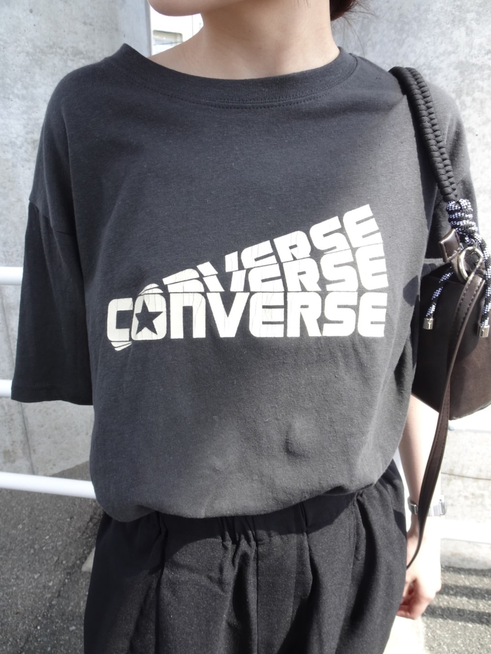 グレー系のTシャツ/カットソー、ブラック系のスラックス、グレー系のショルダーバッグを着用したレディースの春コーディネートの3枚目の写真
