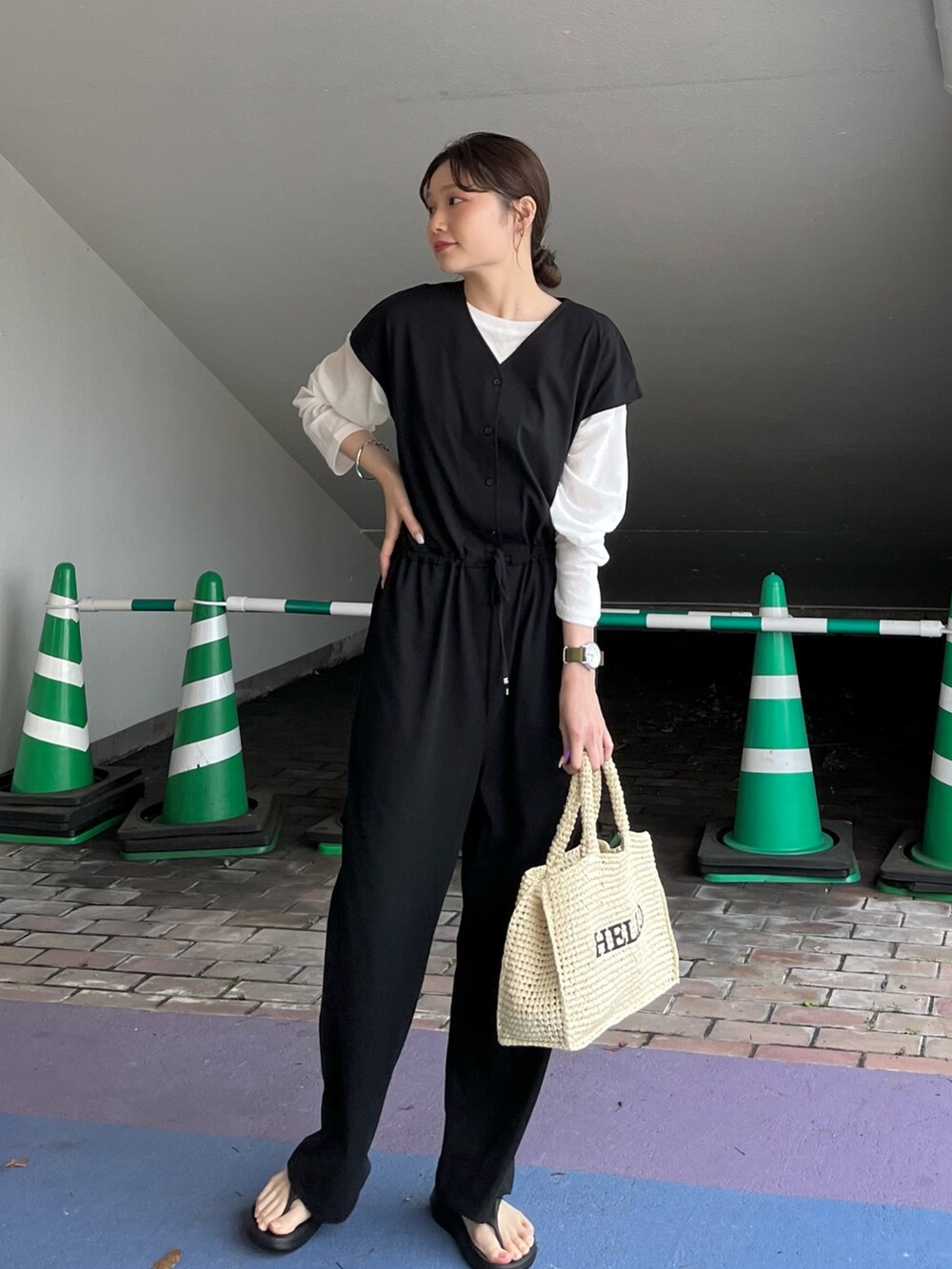 ブラック系のサロペット/オーバーオール、ホワイト系のTシャツ/カットソー、ベージュ系のかごバッグを着用したレディースの春コーディネートの3枚目の写真