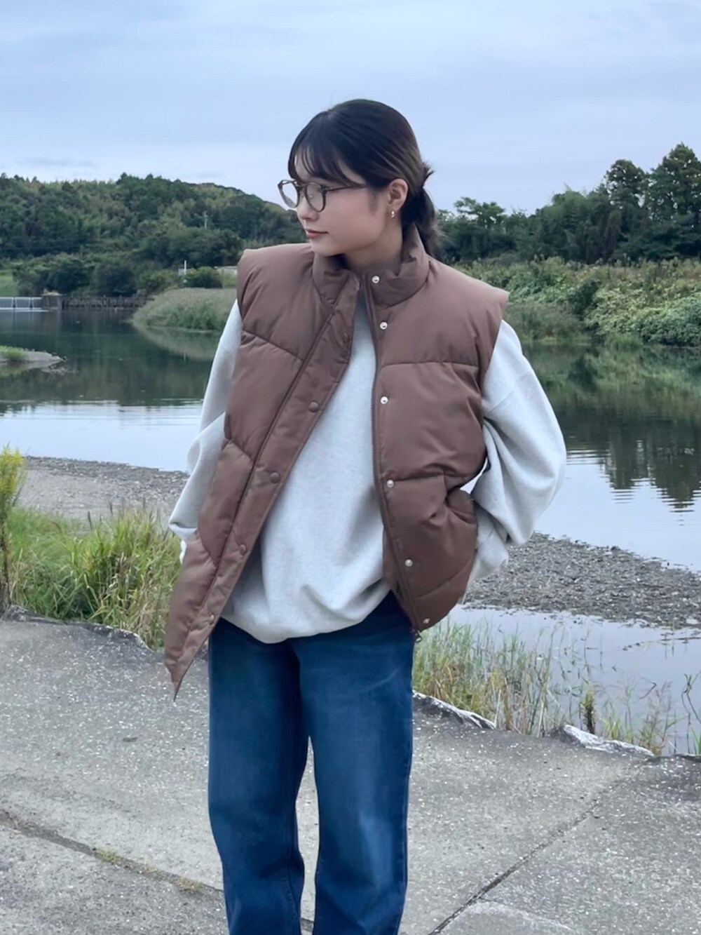 ブルー系のデニムパンツ、グレー系のスウェット、ブラウン系のベストを着用したレディースの秋コーディネートの2枚目の写真