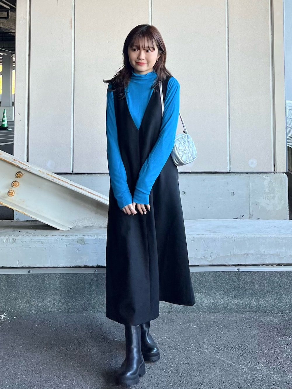 ブラック系のブーツ、ブラック系のジャンパースカート、ブルー系のTシャツ/カットソーを着用したレディースの冬コーディネートの2枚目の写真
