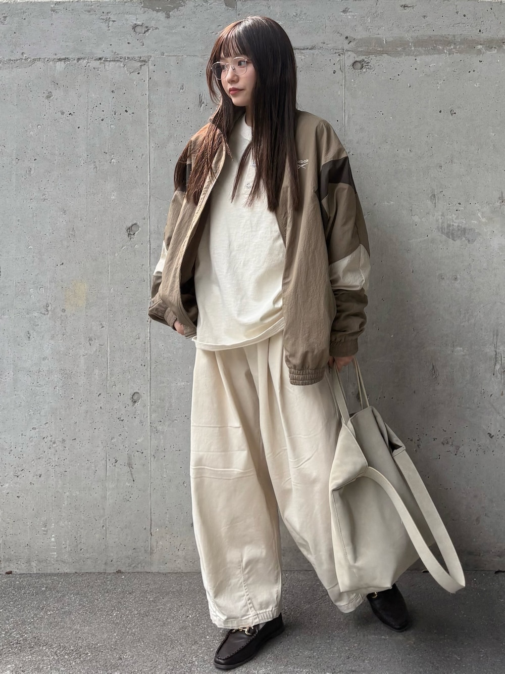 ベージュ系のナイロンジャケット、ベージュ系のチノパンツ、ベージュ系のショルダーバッグを着用したレディースの春コーディネートの2枚目の写真