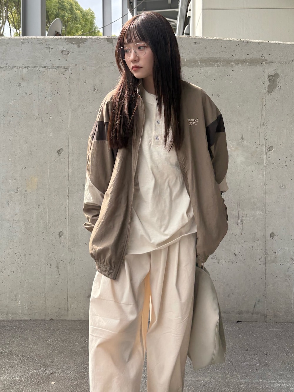 ベージュ系のナイロンジャケット、ベージュ系のチノパンツ、ベージュ系のショルダーバッグを着用したレディースの春コーディネートの5枚目の写真