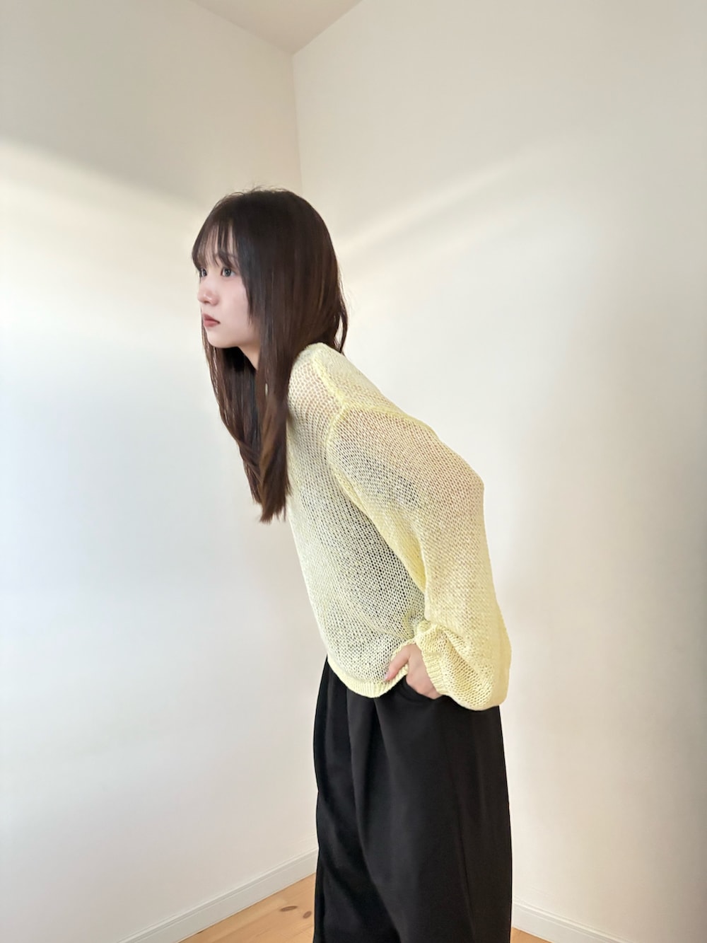 イエロー系のニット/セーター、ブラック系のスラックスを着用したレディースの春コーディネートの3枚目の写真