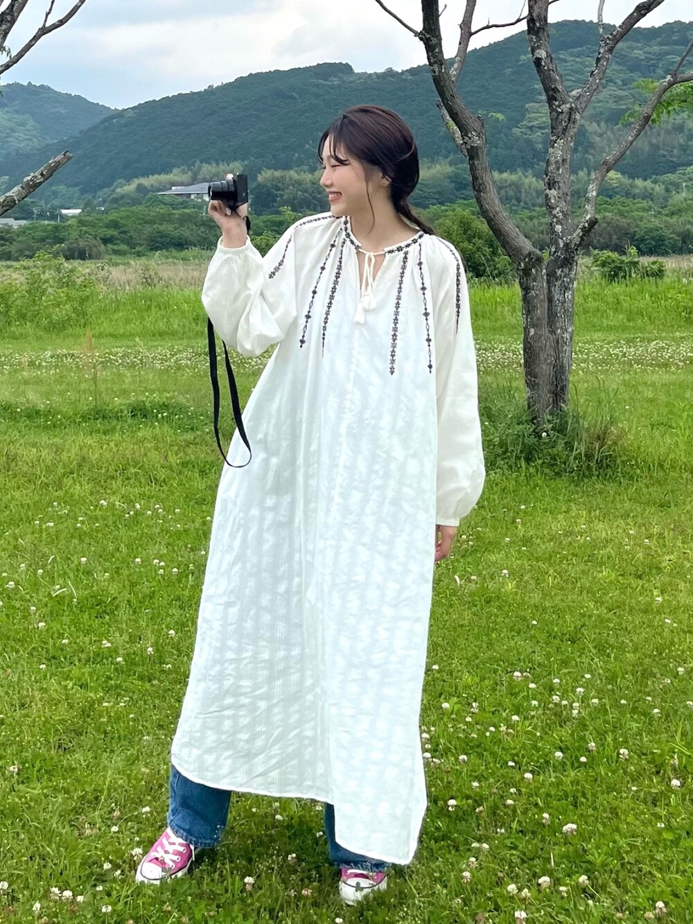 ホワイト系のワンピース、ホワイト系のキャミソール、ブルー系のデニムパンツを着用したレディースの春コーディネートの3枚目の写真