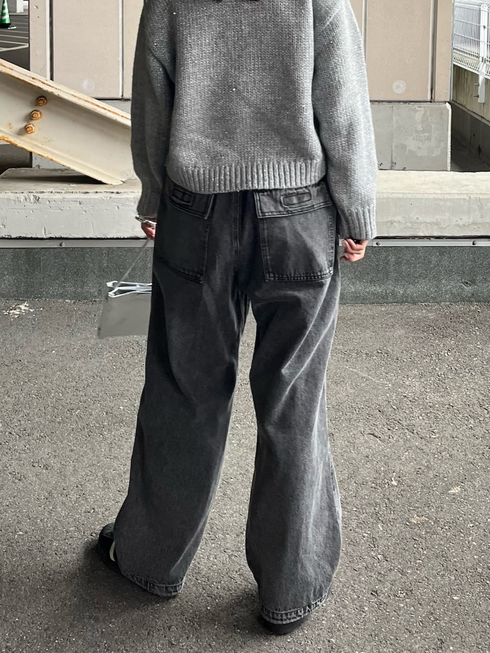 グレー系のニット/セーター、グレー系のデニムパンツ、シルバー系のショルダーバッグを着用したレディースの冬コーディネートの2枚目の写真