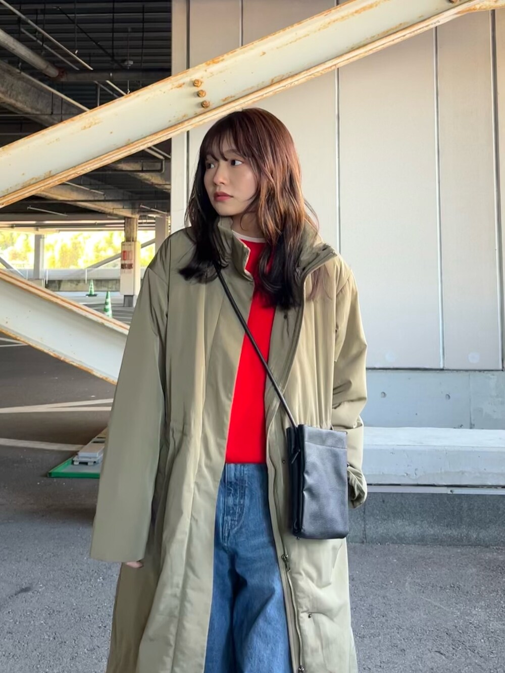 オレンジ系のニット/セーター、グリーン系のその他アウター、ブルー系のデニムパンツを着用したレディースの冬コーディネートの3枚目の写真