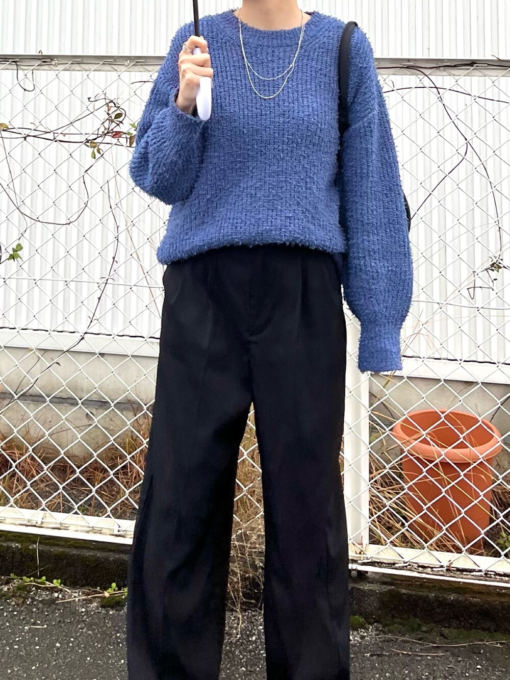 ブルー系のニット/セーター、ブラック系のショルダーバッグ、ブラック系のスラックスを着用したレディースの冬コーディネートの2枚目の写真
