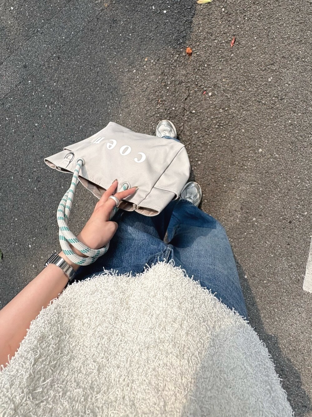 ホワイト系のベスト、ブルー系のデニムパンツ、グレー系のトートバッグを着用したレディースの夏コーディネートの4枚目の写真